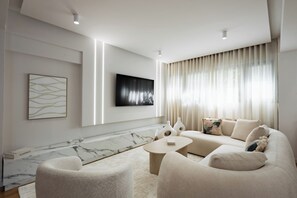A modern living room with a marble accent wall, a flat-screen TV, a beige sofa, and a coffee table. - Acropolis Soul (Athens)