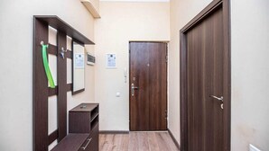 Un couloir étroit avec un banc en bois, une serviette verte suspendue et une porte sur laquelle est affiché un panneau.