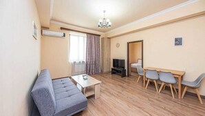 Un salon moderne comprenant un canapé, une table basse, un téléviseur et un coin repas avec des chaises.