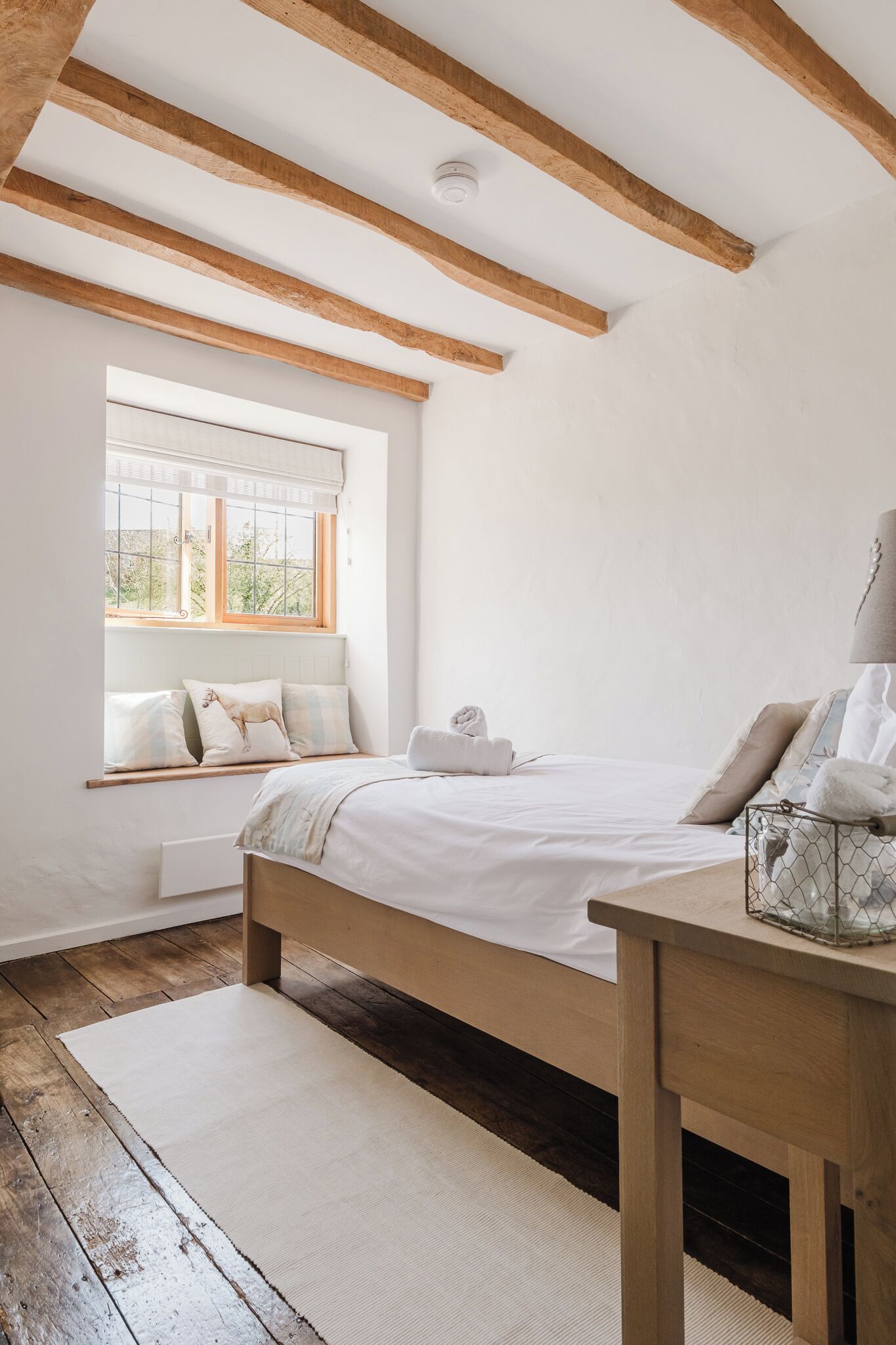 A bedroom with a wooden bed, a window with a view, and a bedside table.