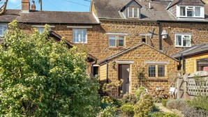 A stone house with a garden, a wooden fence, and a clear sky. - Sweetheart Cottage-Cosy 2BD in Cotswolds (Banbury)