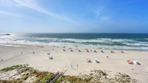 Ein Strand mit Sonnenschirmen, einem Steg und einer Flagge.