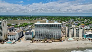 Ein Hotel direkt am Strand mit mehreren Gebäuden, einem Pool und Strandzugang.