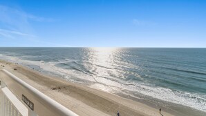 Ein Strand mit einem 'No Smoking'-Schild, blauem Himmel und ruhiger Wellen.