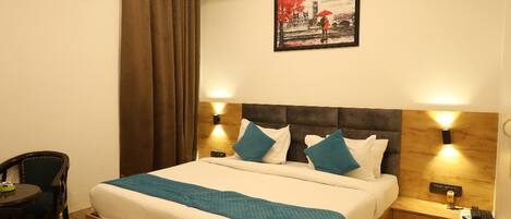 A neatly arranged bedroom with a bed, bedside tables, a chair, a rug, and a painting on the wall.