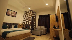 A bedroom with a bed, a sofa, a TV, and a wooden partition. - RADHA BIHARI NIKUNJ INN & RESTAURANT (Vrindavan)