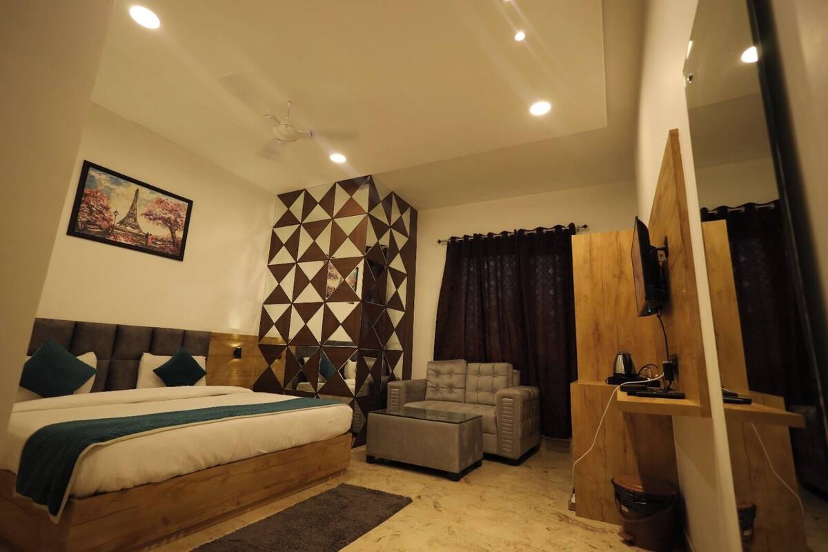 Un dormitorio con cama, sofá, televisión y un separador de madera.