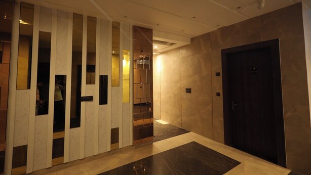 A modern hallway with a dark door, a reception area with a counter, and a patterned wall. - RADHA BIHARI NIKUNJ INN & RESTAURANT (Vrindavan)