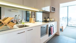 A modern kitchen with a built-in microwave, stainless steel appliances, and a large window offering a city view. - City Views Apt - FREE Parking , WIFI, Gym, + Pool! (Melbourne)