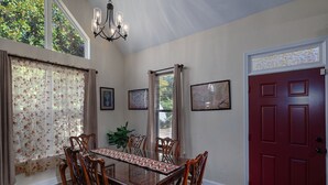 A dining room with a glass table, wooden chairs, a red door, and framed artwork on the walls. - Foxwood Retreat, just minutes from Harrah's Casino in downtown Cherokee (Whittier)
