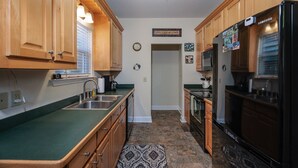 A kitchen with wooden cabinets, a stainless steel sink, a refrigerator, and a clock on the wall. - Foxwood Retreat, just minutes from Harrah's Casino in downtown Cherokee (Whittier)