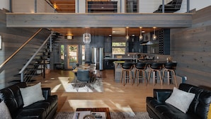 A spacious loft-style living area with a kitchen and dining space, featuring a staircase, wooden floors, and modern furnishings.