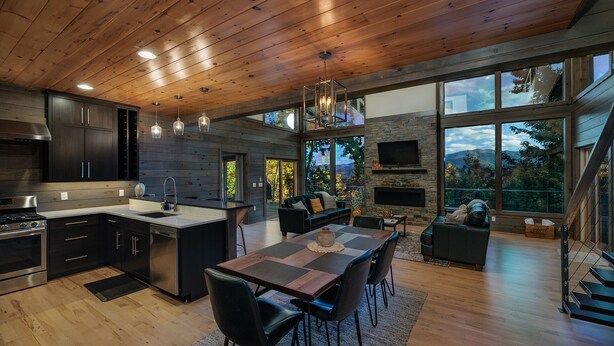 A modern kitchen with wooden cabinets, a central island, and a dining area with a table and chairs.
