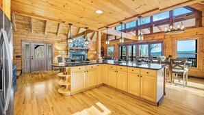 Una cocina amplia con armarios de madera, una isla central y grandes ventanales que ofrecen vistas al exterior.