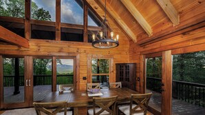 Una cabaña de madera con comedor, que incluye una mesa y sillas, ventanas amplias y vistas al exterior.