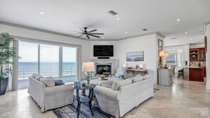 A spacious living room with a large window overlooking the ocean, a fireplace, and a dining area. - Sea Haven - Oceanfront home w/beach access & deck (Ponte Vedra Beach)