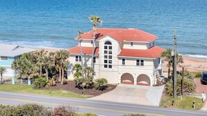 A two-story building with a red-tiled roof, a large arched entrance, and a view of the ocean. - Sea Haven - Oceanfront home w/beach access & deck (Ponte Vedra Beach)