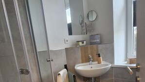 Ein modernes Badezimmer mit einer Duschkabine, einem Waschbecken mit Holzschrank und einem kleinen Teppich.