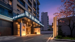 A hotel entrance with illuminated signage, a gated driveway, and a landscaped area with a tree. - MEHOOD LESTIE Hotel Guangzhou Tianhe Financial City (Guangzhou)