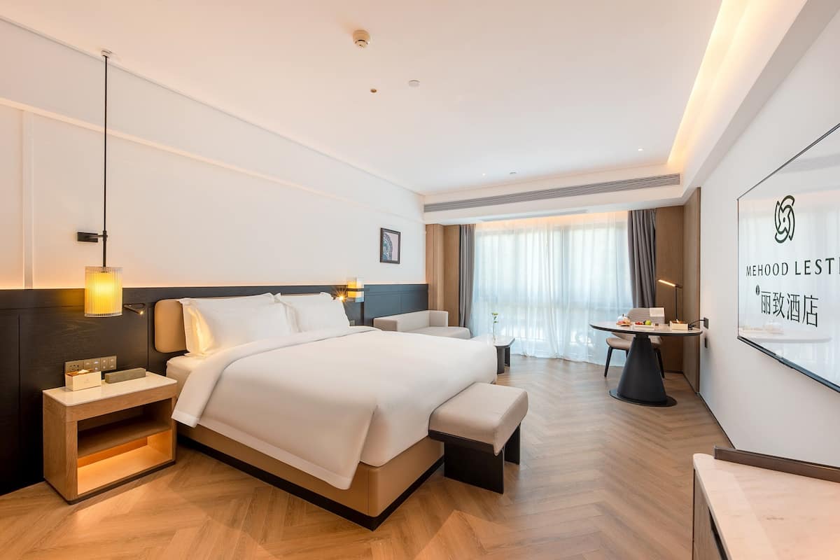 Una camera d'hotel moderna con un letto grande, comodini, una scrivania e vista sulla città.