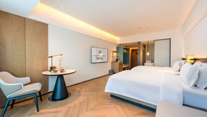 A modern hotel room with a large bed, a seating area with a table, and a mirror. - MEHOOD LESTIE Hotel Guangzhou Tianhe Financial City (Guangzhou)