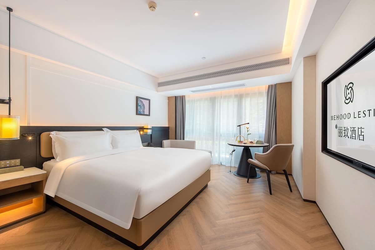 Una camera d'albergo con un letto grande, comodini, una scrivania e una sedia.