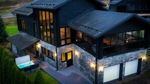 A modern two-story house with a large garage, a hot tub, and a well-lit outdoor area. - Villa Nevada, Northwest-Himos Ski-in/out (Jämsä)