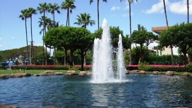A fountain in a landscaped area with palm trees and a clear sky. - Kamaole Sands #4-110 Ground Floor, Full A/C, Great Location, Fitness Center! (Kihei)