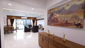 A spacious lobby with a marble floor, a wooden reception desk, and a large painting of a desert scene. - 3 Bedroom Apartment ( Gagal Home) (Mumbai)