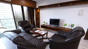 A modern living room with leather sofas, a coffee table, a flat-screen TV, and decorative plants. - 3 Bedroom Apartment ( Gagal Home) (Mumbai)