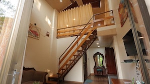 Amplia sala de estar con escalera de madera, un sofá, una mesa de centro y un televisor.