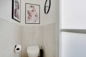 A modern bathroom with a toilet, toilet paper, and a hand dryer.