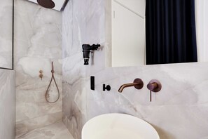 A bathroom with a marble wall, a shower, a toilet, and a dark curtain.
