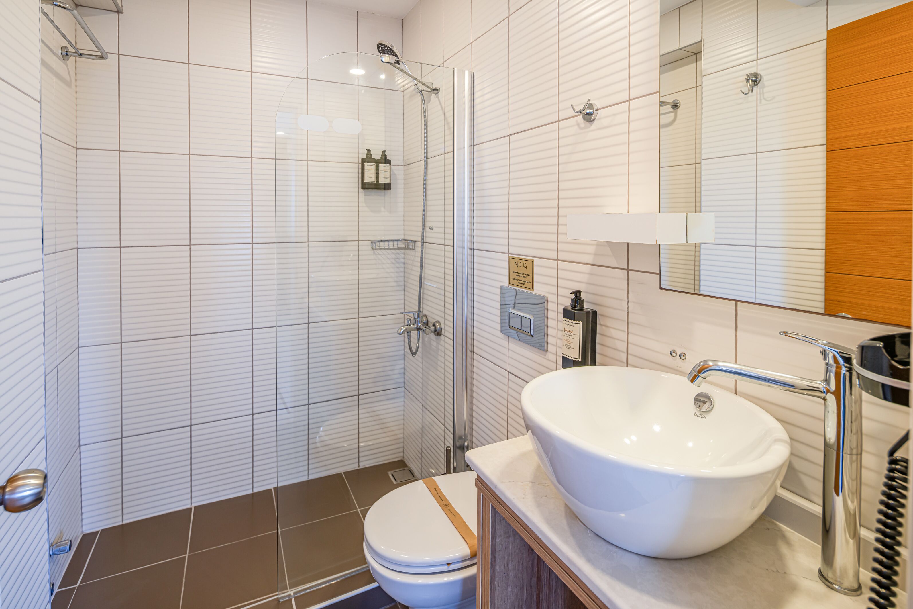 Een badkamer met een witte wastafel, een spiegel en een douche.