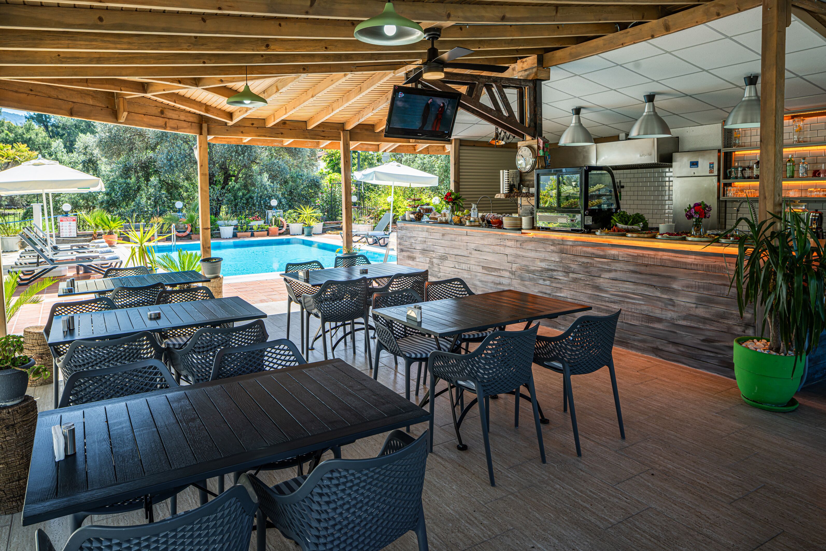 An outdoor patio with tables and chairs, a pool, and a kitchen area.