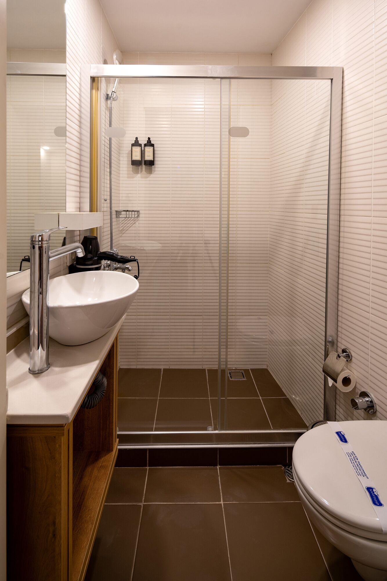 A modern bathroom with a large white sink, a glass shower enclosure, and a toilet.