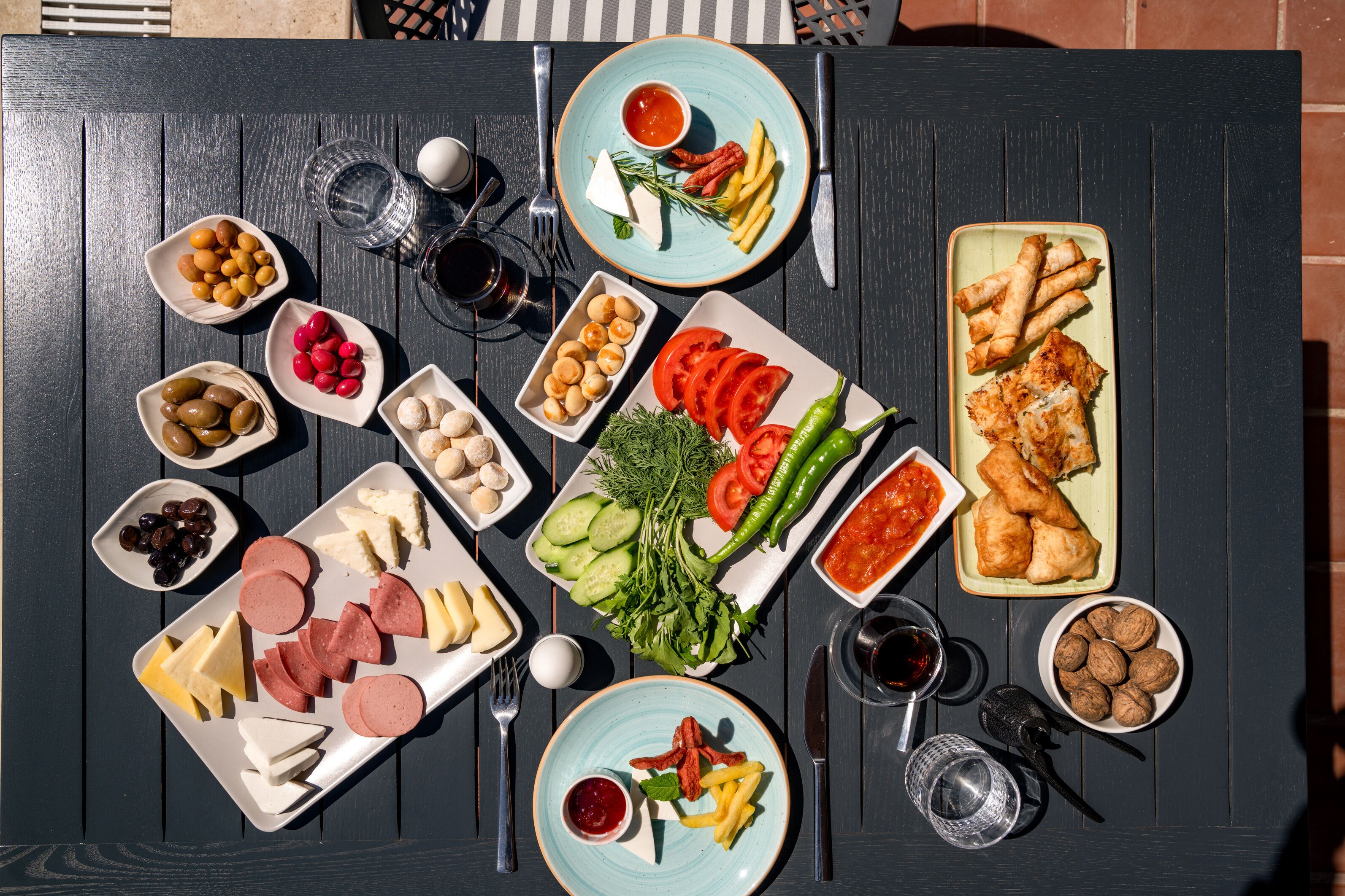 A table with various food items and condiments, including olives, cheese, meats, and vegetables.
