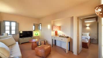 A modern hotel room with a sofa, a TV, a lamp, a small table, and a bed.