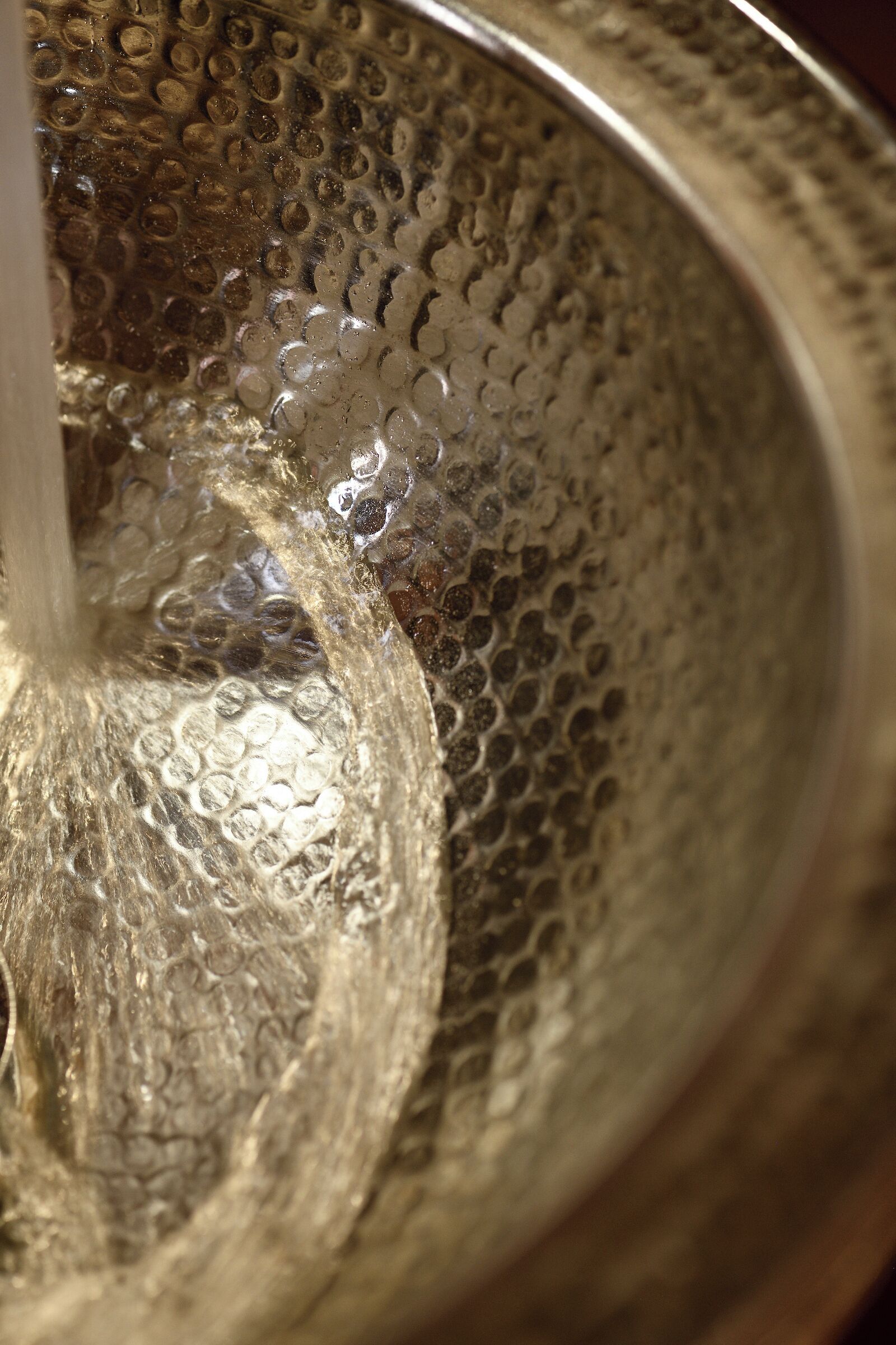 Un primer plano de una superficie metálica con textura, con un hilo de agua que fluye sobre ella.