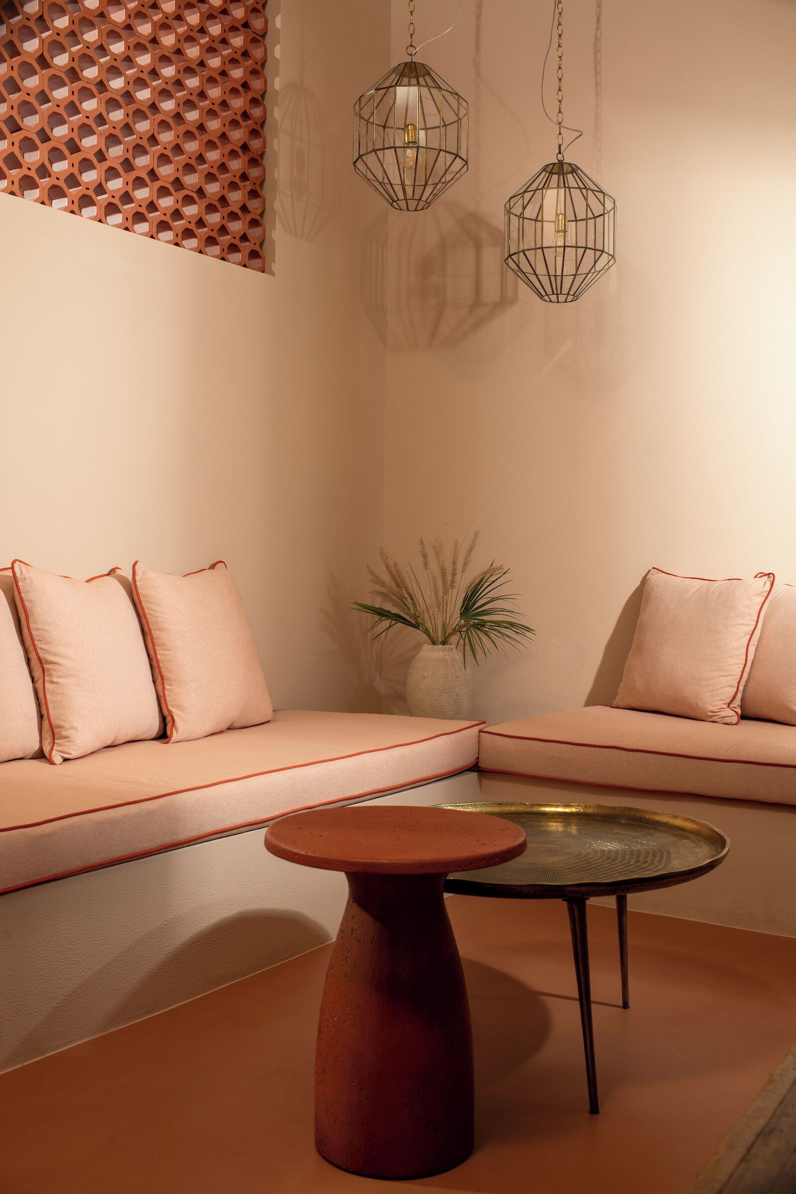 A modern living room with a beige sofa, a round coffee table, and two hanging light fixtures.