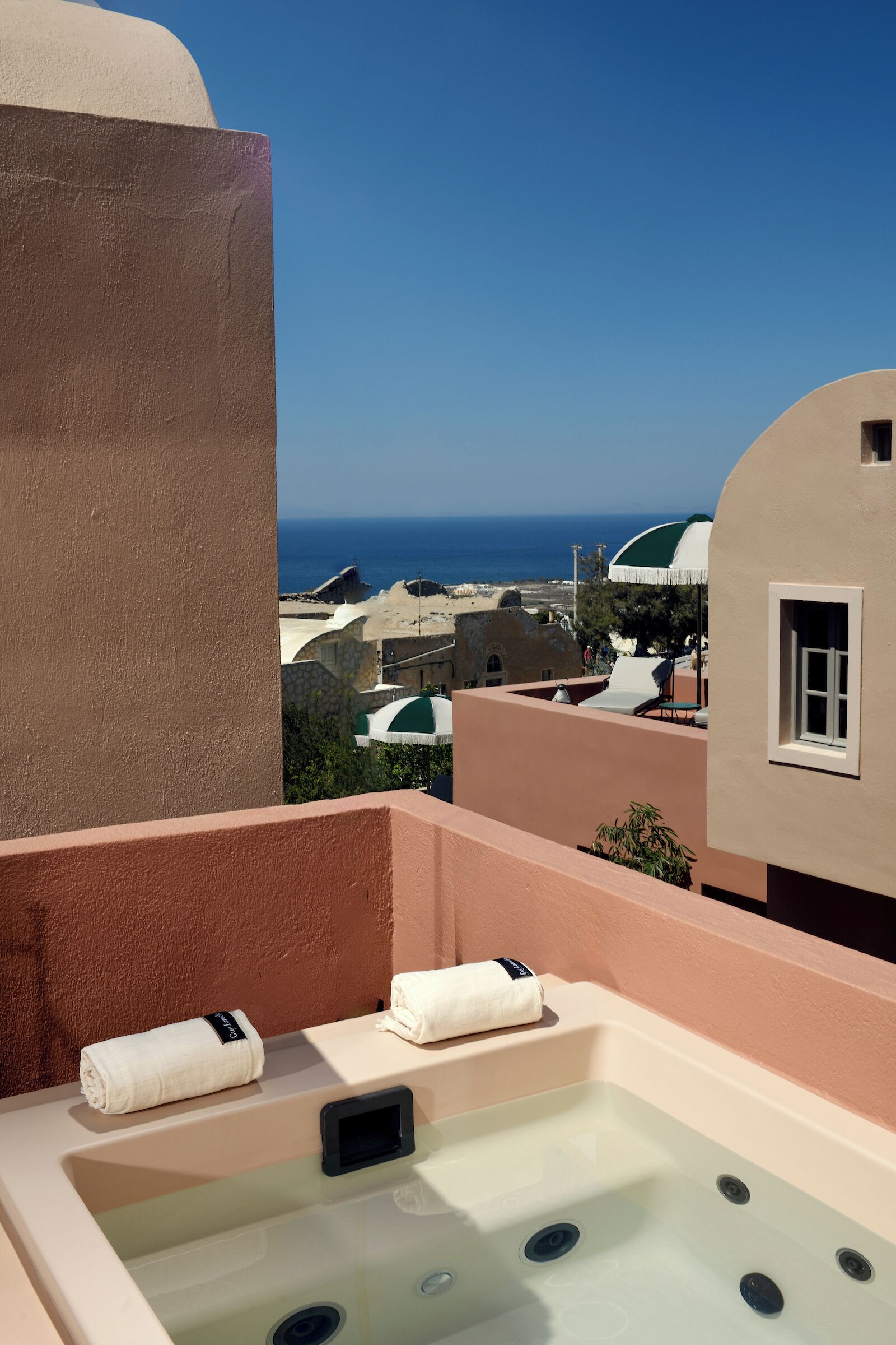 Boblebad på en balkon med udsigt over havet og traditionel arkitektur.