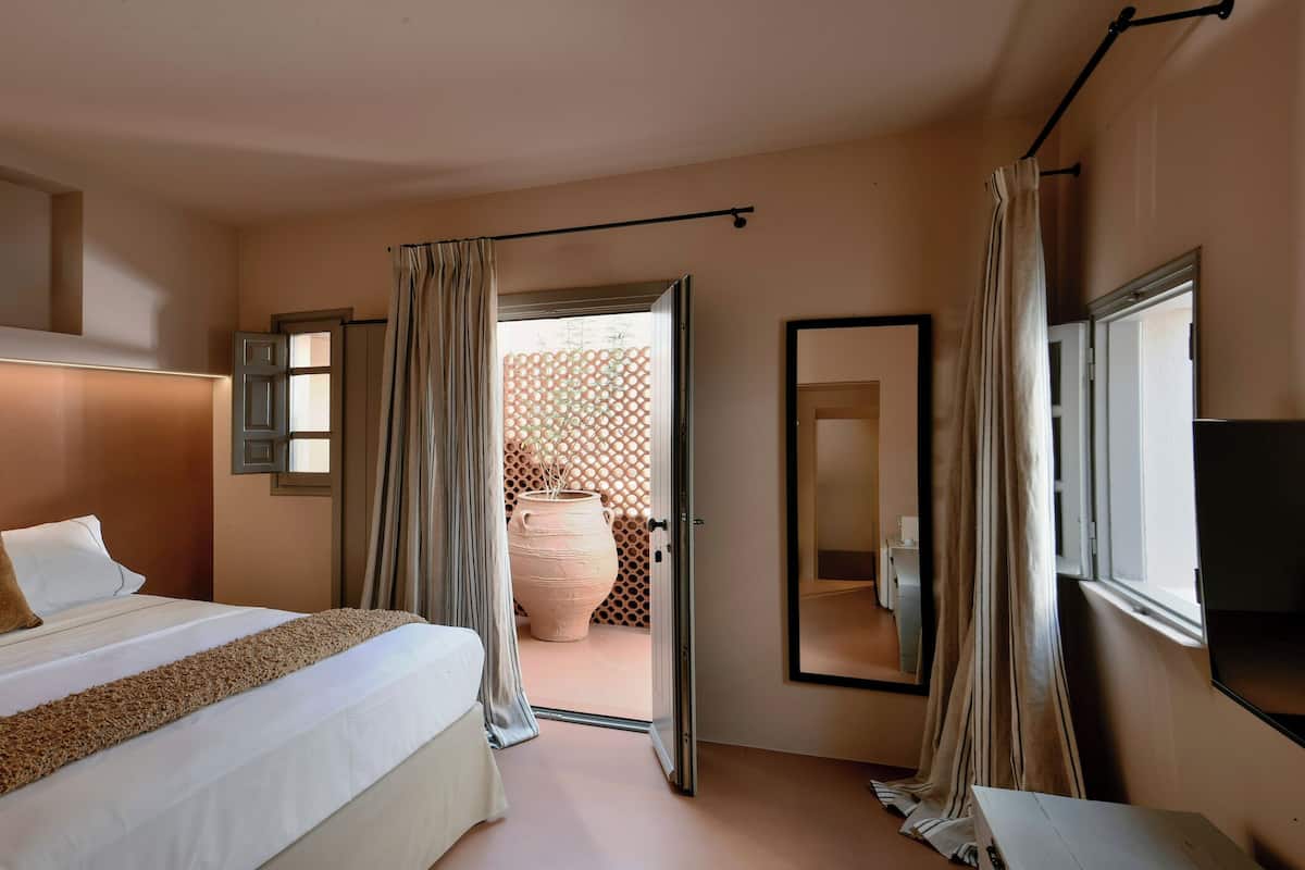 Een hotelkamer met een groot bed, een flatscreen televisie, een raam met gordijnen en uitzicht op buiten.
