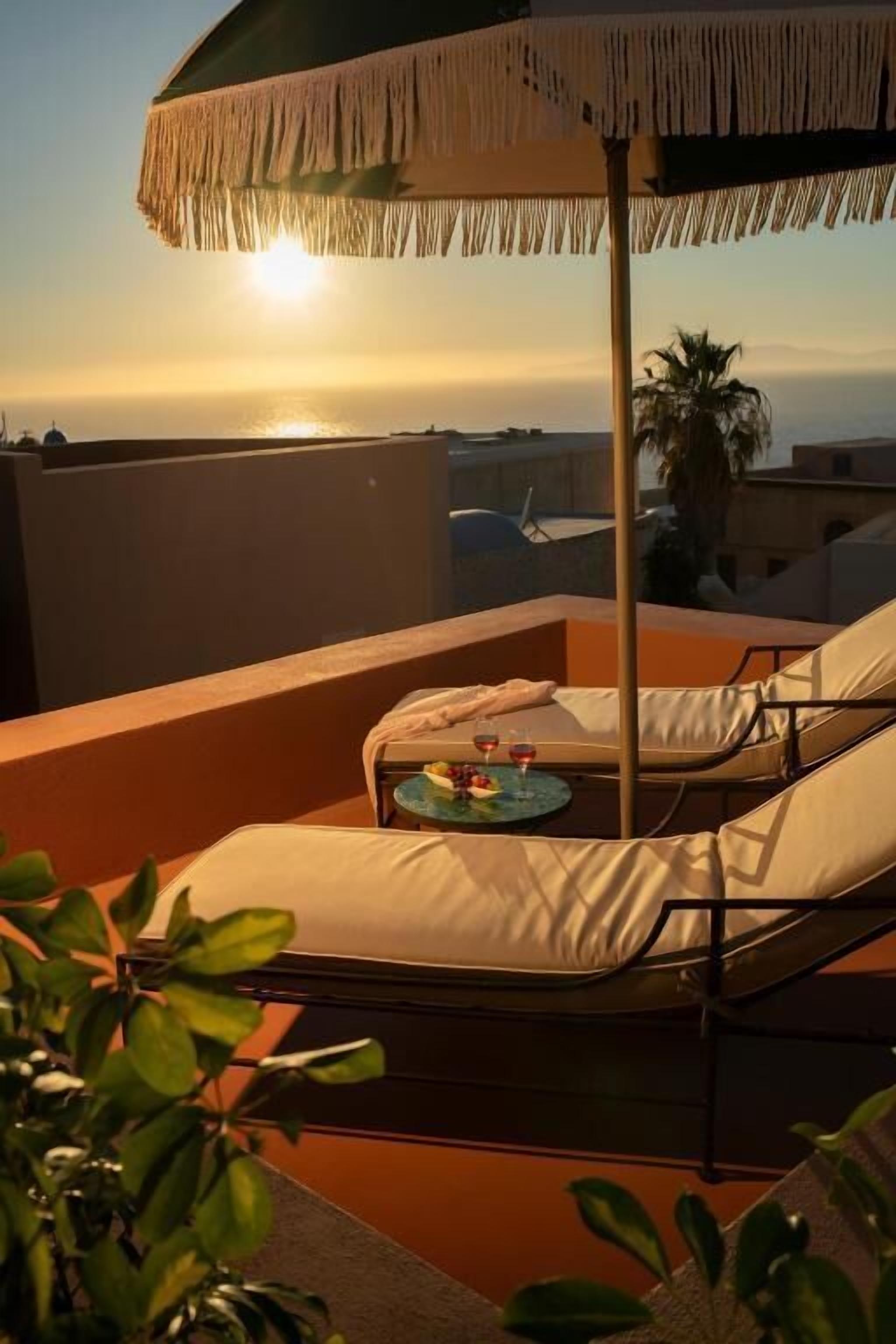 A rooftop terrace with a lounge chair, a small table with drinks, and a decorative umbrella.