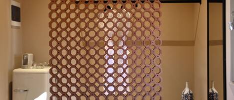 A bathroom with a wooden lattice partition, a white sink, and two decorative vases.
