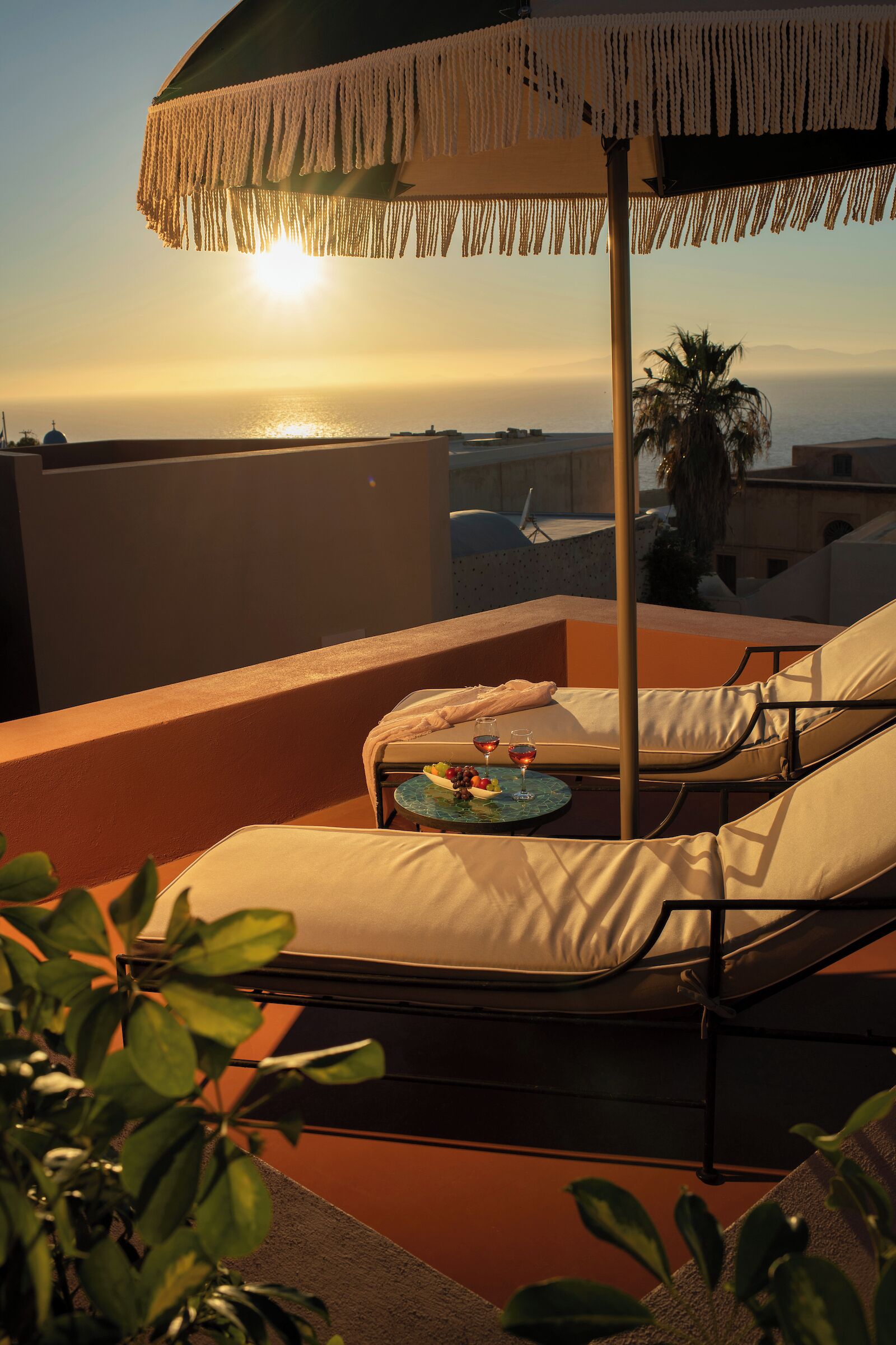 A rooftop terrace with a lounge chair, a small table with drinks, and a decorative umbrella.