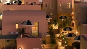 A hotel with white buildings, a pool, and umbrellas. - Terra Verde Oia by K&K (Santorini)