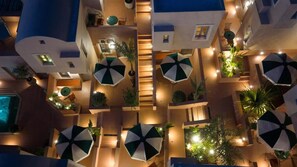 Een hotelatrium met meerdere niveaus, verschillende balkons, zitgedeeltes buiten en een centrale trap.
