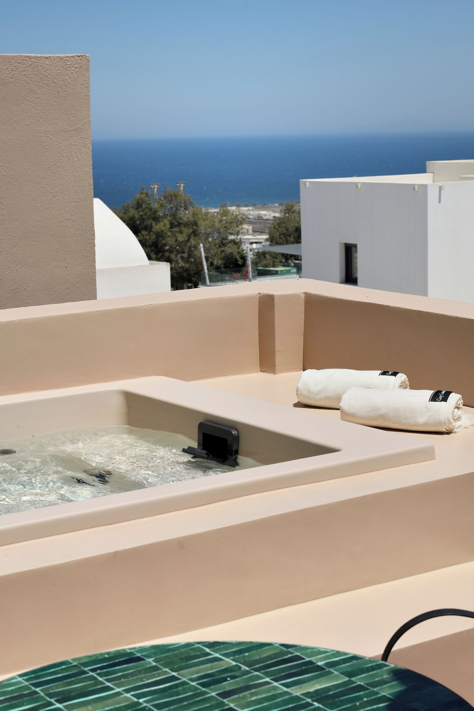 A rooftop terrace with a hot tub, two towels, and a view of the sea.