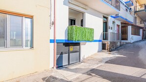Un edificio residencial de varios pisos, con un balcón, una puerta de garaje y un ventanal visible.