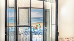 Un balcón con una mesa dispuesta para dos personas, con vista al mar.